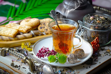 Sweet, hot tea with dry tea leaves, on an old background.