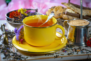 Sweet, hot tea with dry tea leaves, on an old background.