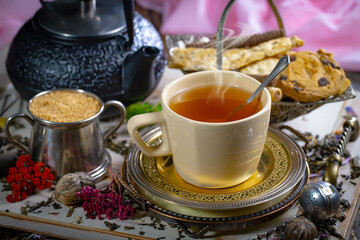 Sweet, hot tea with dry tea leaves, on an old background.