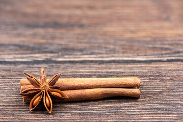 Cinnamon sticks and star anise on a wooden background close-up.