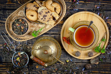 Fototapeta na wymiar Sweet, hot tea with dry tea leaves, on an old background.