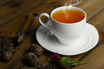 Sweet, hot tea with dry tea leaves, on an old background.