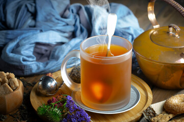 Sweet, hot tea with dry tea leaves, on an old background.