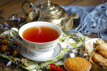 Sweet, hot tea with dry tea leaves, on an old background.