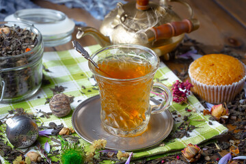 Sweet, hot tea with dry tea leaves, on an old background.