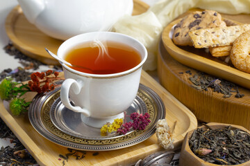 Sweet, hot tea with dry tea leaves, on an old background.