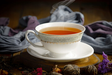 Sweet, hot tea with dry tea leaves, on an old background.