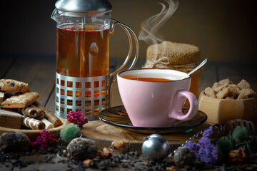 Sweet, hot tea with dry tea leaves, on an old background.