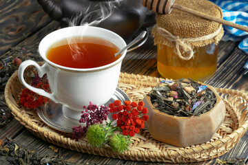 Sweet, hot tea with dry tea leaves, on an old background.