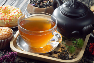 Sweet, hot tea with dry tea leaves, on an old background.