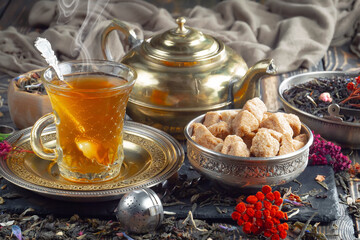 Sweet, hot tea with dry tea leaves, on an old background.