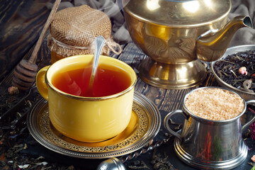 Sweet, hot tea with dry tea leaves, on an old background.
