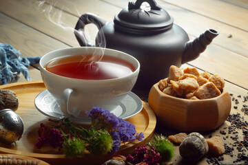 Sweet, hot tea with dry tea leaves, on an old background.