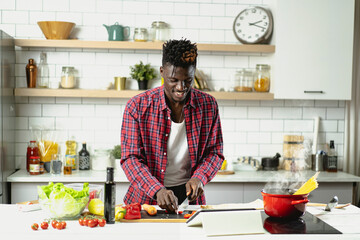 African man cooking in modern kitchen. Handsome chef preparing food.