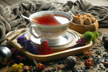 Sweet, hot tea with dry tea leaves, on an old background.