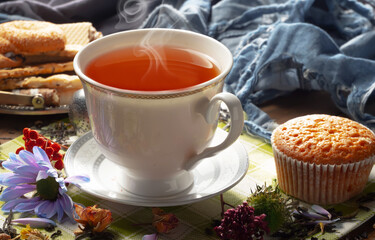 Sweet, hot tea with dry tea leaves, on an old background.