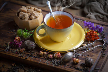 Sweet, hot tea with dry tea leaves, on an old background.