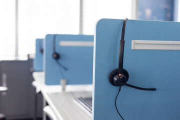 Black headset for operator are neatly stored next to the call center desk for worker working customer service and marketing support. Office supplies of customer service. 
