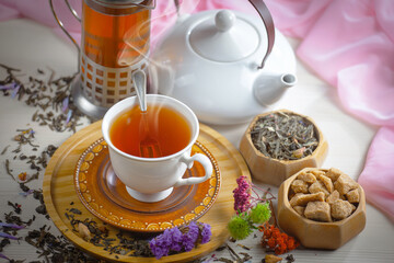 Sweet, hot tea with dry tea leaves, on an old background.