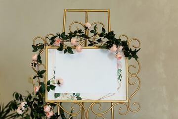 Closeup of wedding floral gold coloured welcome board and easel decorated with roses
