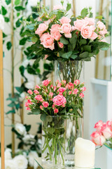 Closeup vertical shot of natural roses with vibrant colours arranged in glasses on a wedding day