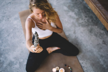 Young crop woman making prayer on mat with wand
