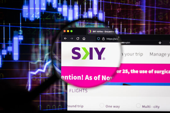 Sky airline company logo on a website with blurry stock market developments in the background, seen on a computer screen through a magnifying glass	
