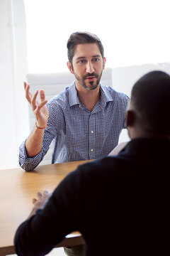 Tell me about your previous work experience. a businessman interviewing a job applicant in an office.