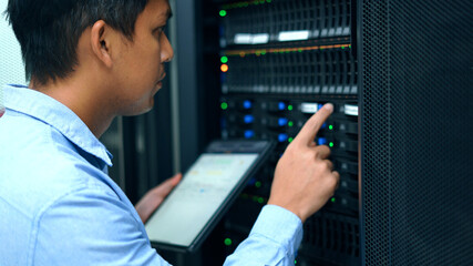 System administrator using digital tablet while working in data center.