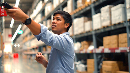 Man worker checking products with barcode scanner in warehouse.