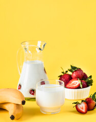 Milk, fresh strawberries and bananas on a yellow background. healthy diet and nutrition, lifestyle.