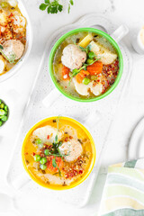 Soup with chicken meatballs and spring vegetables on a white background. Vertical.