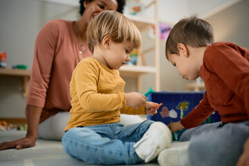 Small boy and his friend play together at kindergarten.
