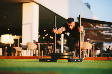 Handsome young man working out in an outdoor gym pushing weights