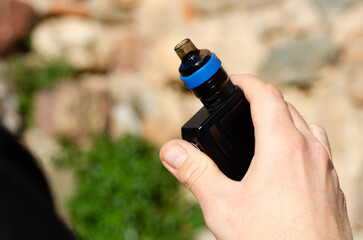 Hand of a man holding an electronic cigarette. Concept of new technologies and harmful substance