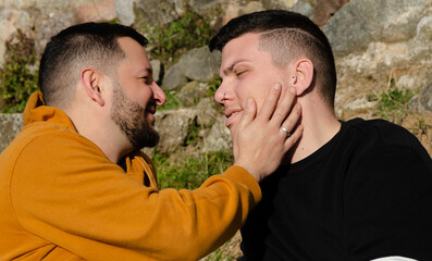 A couple of gay men smile at each other in love. Homosexuality and LGBTQ+ concept.