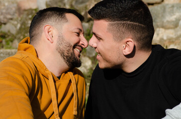 A couple of gay men in love come closer to kiss while smiling at each other. Homosexuality and...