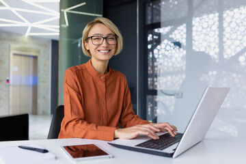 Portrait of happy and successful female programmer inside office at workplace, worker smiling and...
