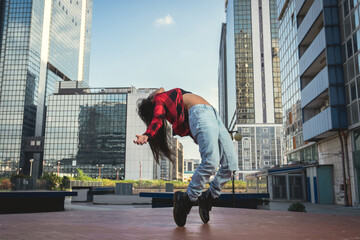 Photo shoot of stylish caucasian hip hop dancer posing on her toes with red shirt, jeans and black...