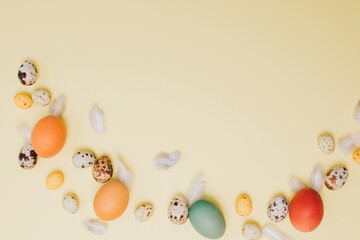 Colored eggs of different sizes on a yellow background. Symbol of the Easter holiday. Easter background. Flat lay