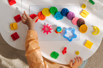 A little girl play with plasticine and creates colorful numbers.  Learning to count through play....
