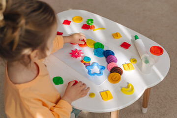 A little girl play with plasticine and creates colorful numbers.  Learning to count through play. Early education. Fine motor skills, creativity and  hobby. - obrazy, fototapety, plakaty