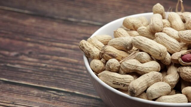 Raw Peanuts And Open Nut In White Bowl Cup On Wooden Board. Dolly Slider Shot. 4k, 60 FPS.