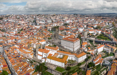 Fototapeta na wymiar Aerial drone perspective of Porto city. View of old historic center. In the middle is Cathedral of Porto. Beautiful landscape with buildings painted in different colours. Rooftop of Porto city
