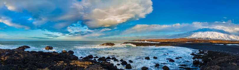 The basalt coast of Iceland washed by the winter storm waves of the Atlantic, and in the background...