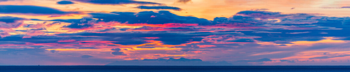 A lonely fishing ship in the ocean under an incredibly colorfully picturesque sky at sunrise....