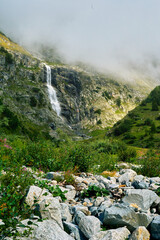 Mountain landscape with a waterfall in the fog. Caucasus, Russia