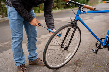 Man fixing a blue fixie bike wearing jeans and a black coat