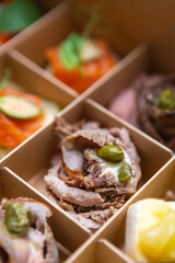Exotic canape snacks delivery. Sliced veal meat with capers delivered in cardboard box for wine party