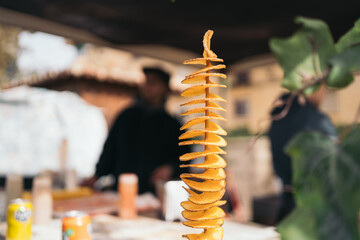 Wooden skewer of potato chips in the shape of a serpentine made in a Spanish medieval market street...
